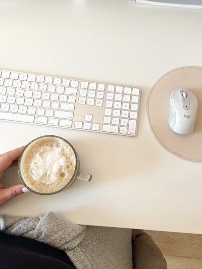Photo from above of a keyboard, mouse, and clear mug of coffee sitting on a desk