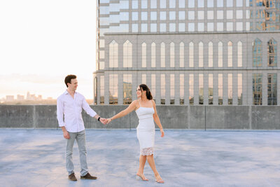 Future bride and groom walk holding hands along the rooftop garage in Tampa, Fl
