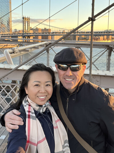 Khim Higgins Photography standing on the Brooklyn bridge with her husband on vacation.