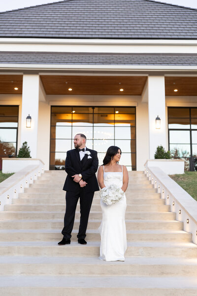 Austin-based wedding photographer captures a heartfelt moment as a bride and groom share an embrace in front of a picturesque park.