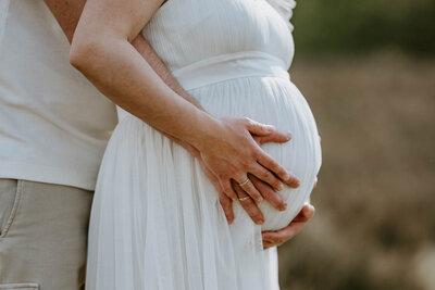 Ein Paar umarmt den Babybauch beim Schwangerschafts-Foto-Shooting mit Lichtsammlerin
