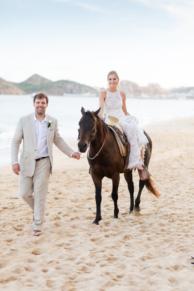 Bride and groom on a beach in Mexico, riding a horse.
