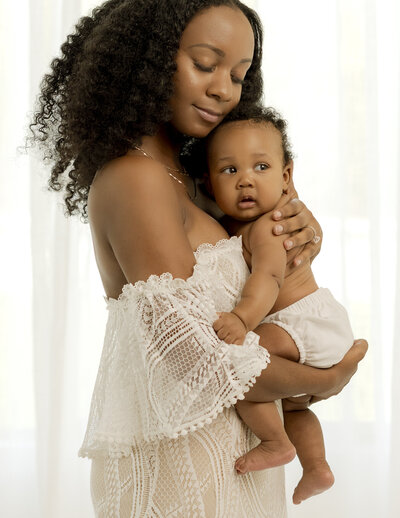beautiful black woman standing and holding her infant