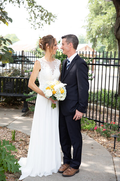 An Austin-based wedding photographer captures a beautiful moment as a bride and groom stand in front of a fence.