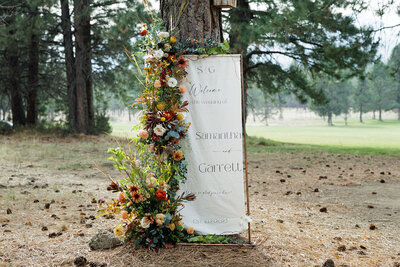 Welcome sign against pine tree with fall wildflowers at Pole Creek Ranch in Sisters Oregon