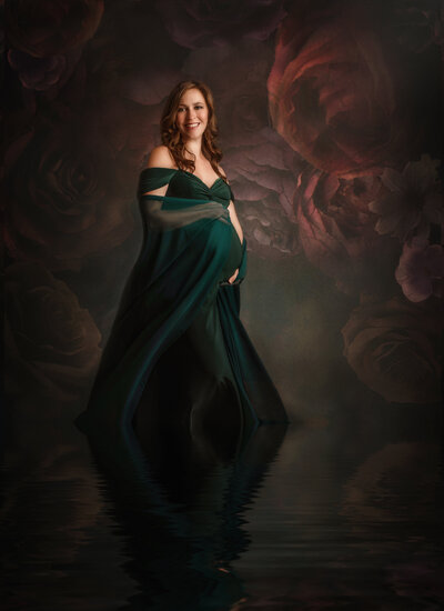 Pregnant woman in red dress embraces her belly for maternity portrait
