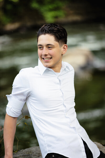 Teenage boy in white dress shirt looking off into distance smilling