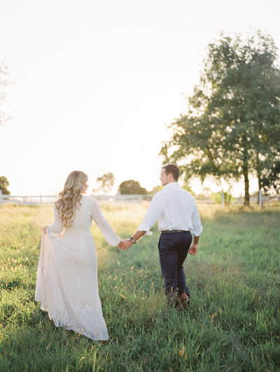 man and woman walking through field during Lancaster engagement session