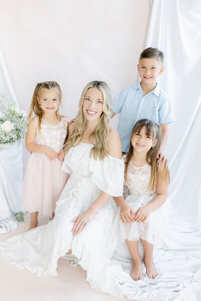 Mom with three kids smiling at new jersey family photographer