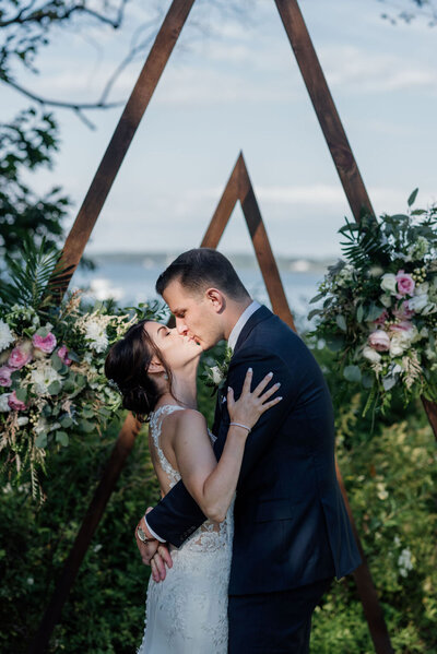A couple share a kiss in front of asymetrical arches