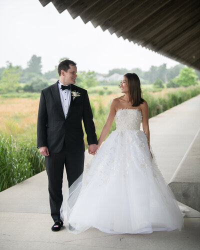 a bride and groom looking at each other on a covered path