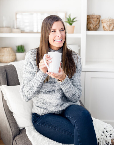 Woman holding the cup smiling while on the couch