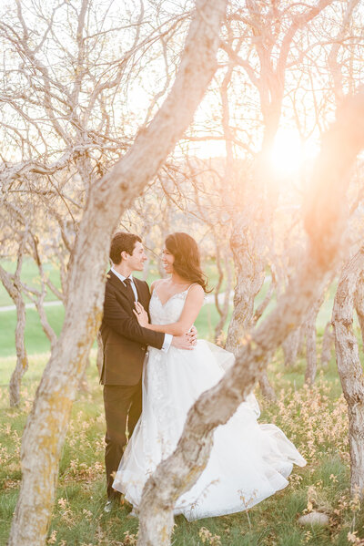 outdoor wedding portraits of bride and groom embracing in a forest with the sun setting through the trees with denver wedding photographer