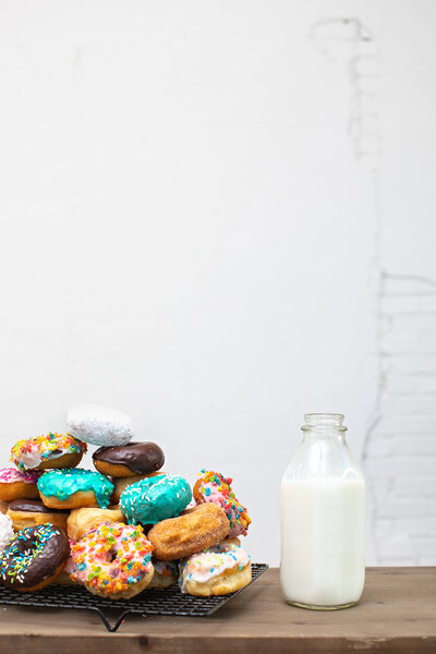 Stacks of Assorted Donuts and Milk Jug to the Right - Daylight Donuts
