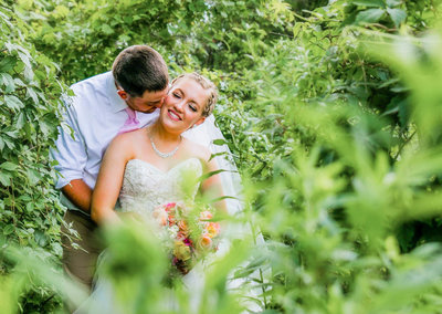 couple in greenery nuzzle on wedding day