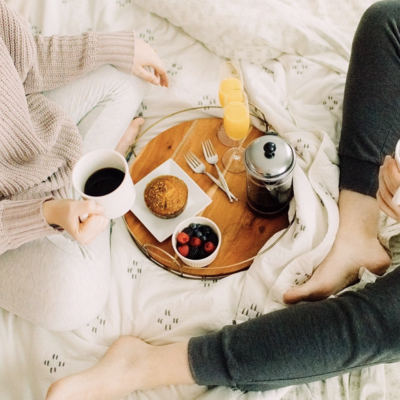 Photo of breakfast in bed on a try with coffee, orange juice, and muffins