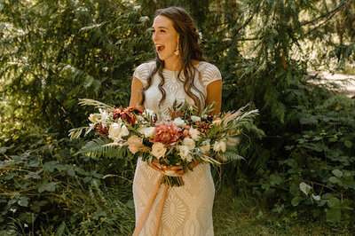 Bride smiling and holding heart shaped wedding ceremony bouquet.