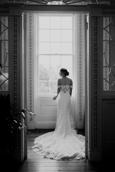Bridal portrait taken at the Govenor Thomas Bennett House in Charleston. Bride standing in front of high window , looking to the side. Photographed through open door.