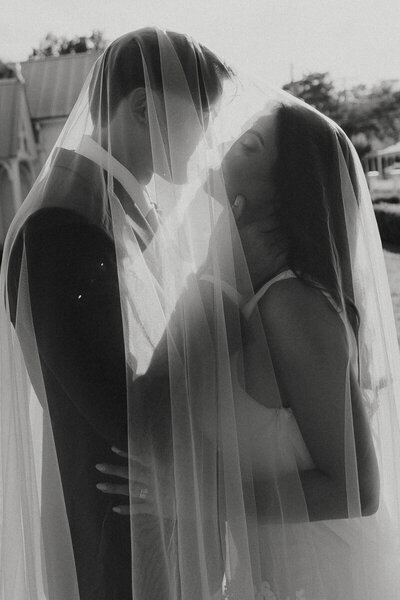 bride and groom embracing for kiss under veil