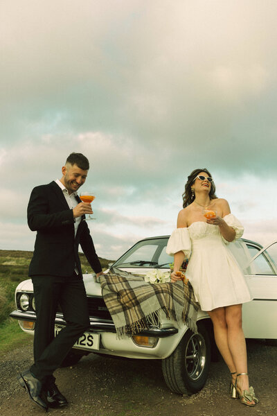 bride and groom stand at classic car