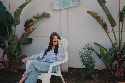 Branding portrait of Sharni Tolhurst sitting outdoors in a striped shirt and sunglasses.