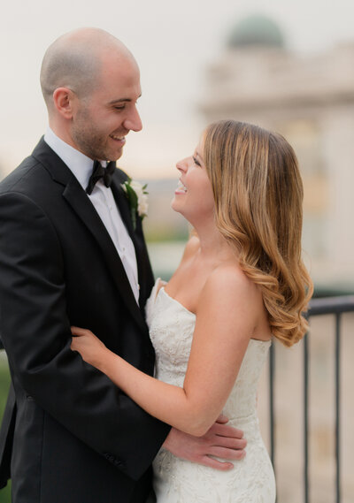 couple laughing on their wedding day on top of the omni parker hotel rooftop for their wedding day in the spring.