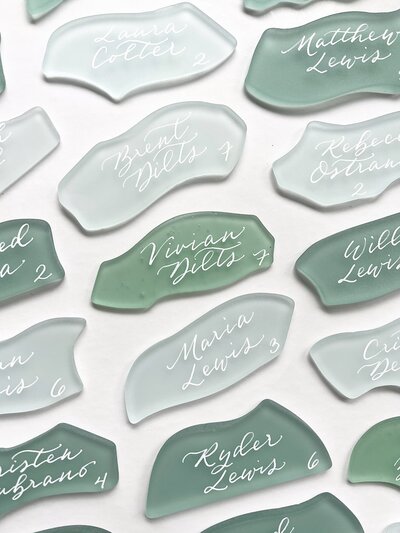 Green sea glass place cards with white calligraphy