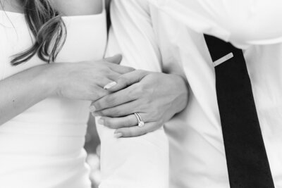 Detail of bride's hands wrapped around groom's arm