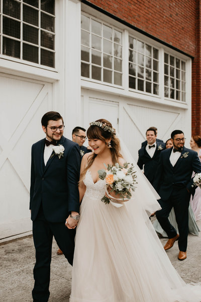 Bride & groom walk hand in hand on their wedding day with their wedding party in Portland, Oregon