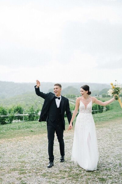 A stunning diverse wedding couple waving happily at their wedding guests at the vineyards featured at a wedding in Birmingham, AL