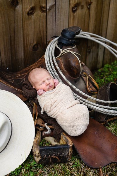 Beautiful Mississippi Newborn Photography:  newborn boy on a horse saddle with cowboy hat