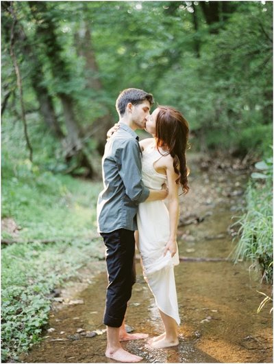 Nature Engagement Photos in the Woods by Colorado Wedding Photography. Bride and Groom Barefoot in a River in Casual Outfits © Bonnie Sen Photography