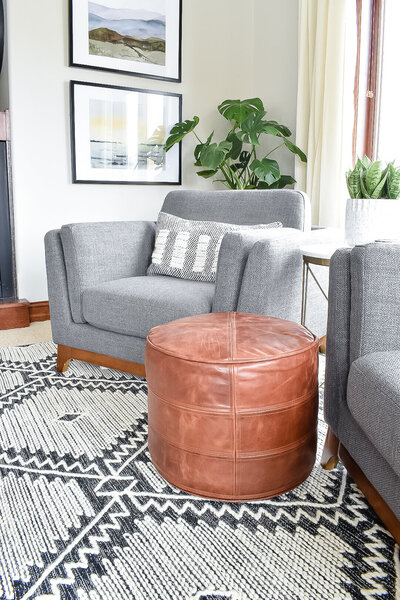 A bright seating area with grey armchairs and a leather footstool