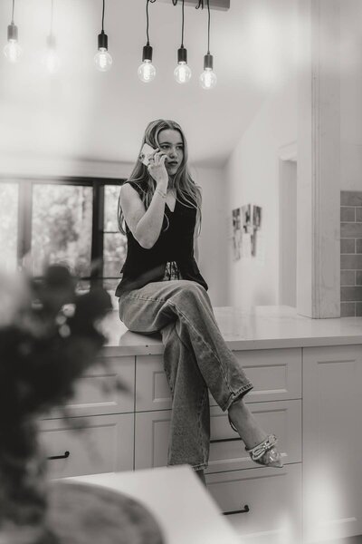 Branding photography showing a business owner on the phone in her kitchen workspace.