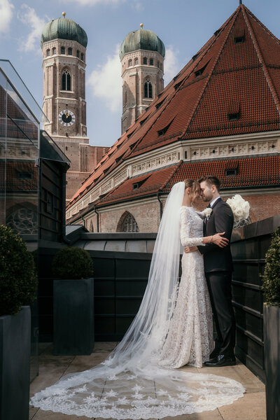 Ein Foto eines Hochzeitspaares auf einer Dachterrasse in München, das sich im Arm hält.