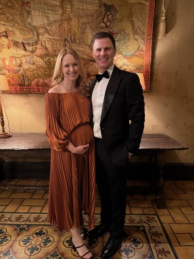 Excited couple smiling as pregnant woman gently holds her baby bump