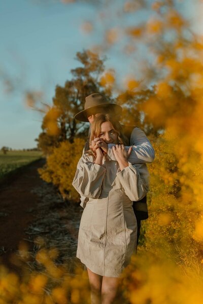 Lifestyle family photography in Central West NSW with mother and child walking through yellow wildflowers.