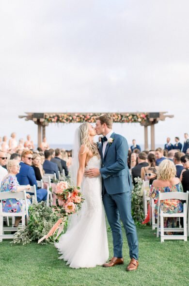 Bride and groom kissing at the end of the aisle Coastal outdoor wedding