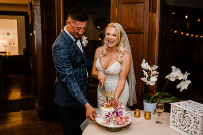 bride and groom smile and cut wedding cake