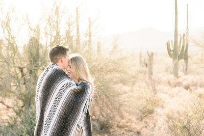 Tucson Desert Engagement Session Photo of Couple Hugging Wrapped in Southwest Blanket | Tucson Wedding Photographer