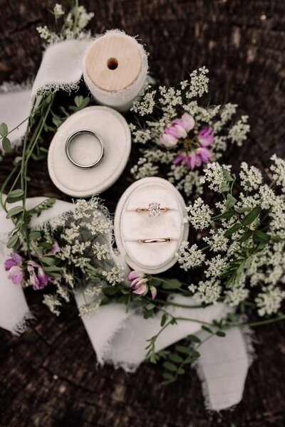 Rustic flatlay with bride and groom rings and wildflowers