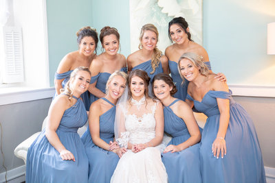 Bride smiles surrounded by her bridesmaids on wedding day