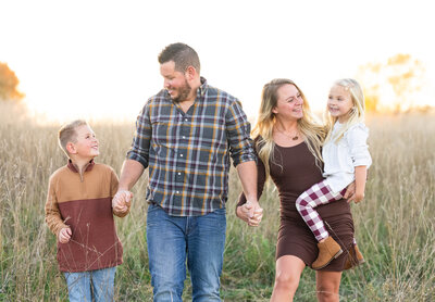 family walking in field laughing