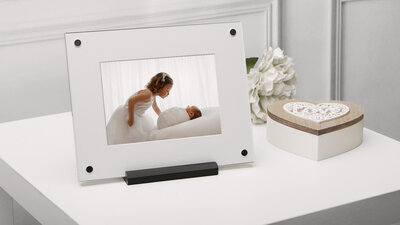 matted printed photo  of a newborn and  his older  sister in a clear  display frame