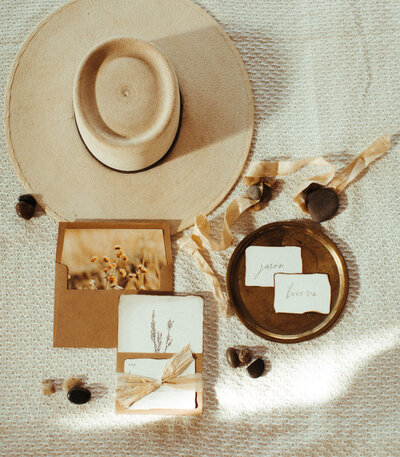 Boho wedding flat lay details with invitations and hat