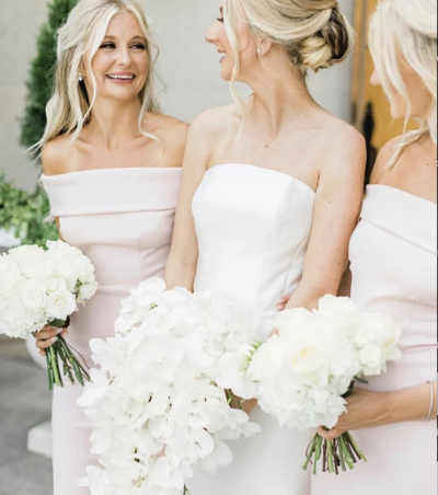 bride standing next to bridesmaid while smiling