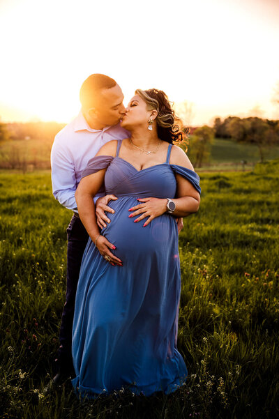 pregnant mom and husband kissing at sunset