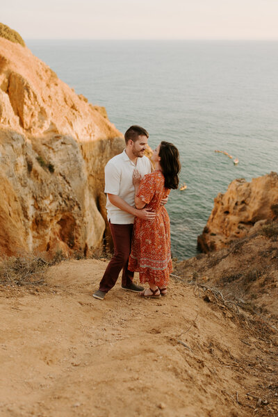 husband and wife Portugal wedding photographers taking in the scenic overlook of the Algarve at golden hour