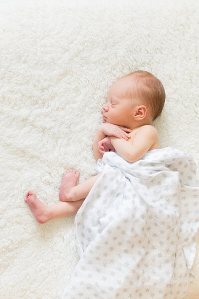 newborn sleeps on soft white blanket