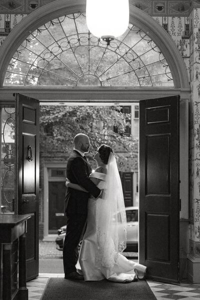 bride and groom embracing while standing in doorway